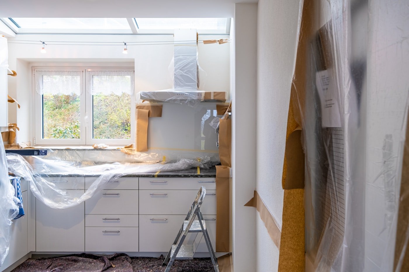Room mid-renovation with furniture covered in plastic sheeting during a DIY paint project