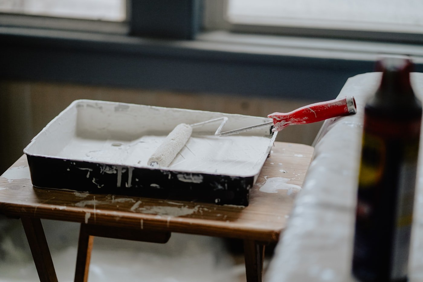 Hand filling a small hole in a wall with filler and a putty knife