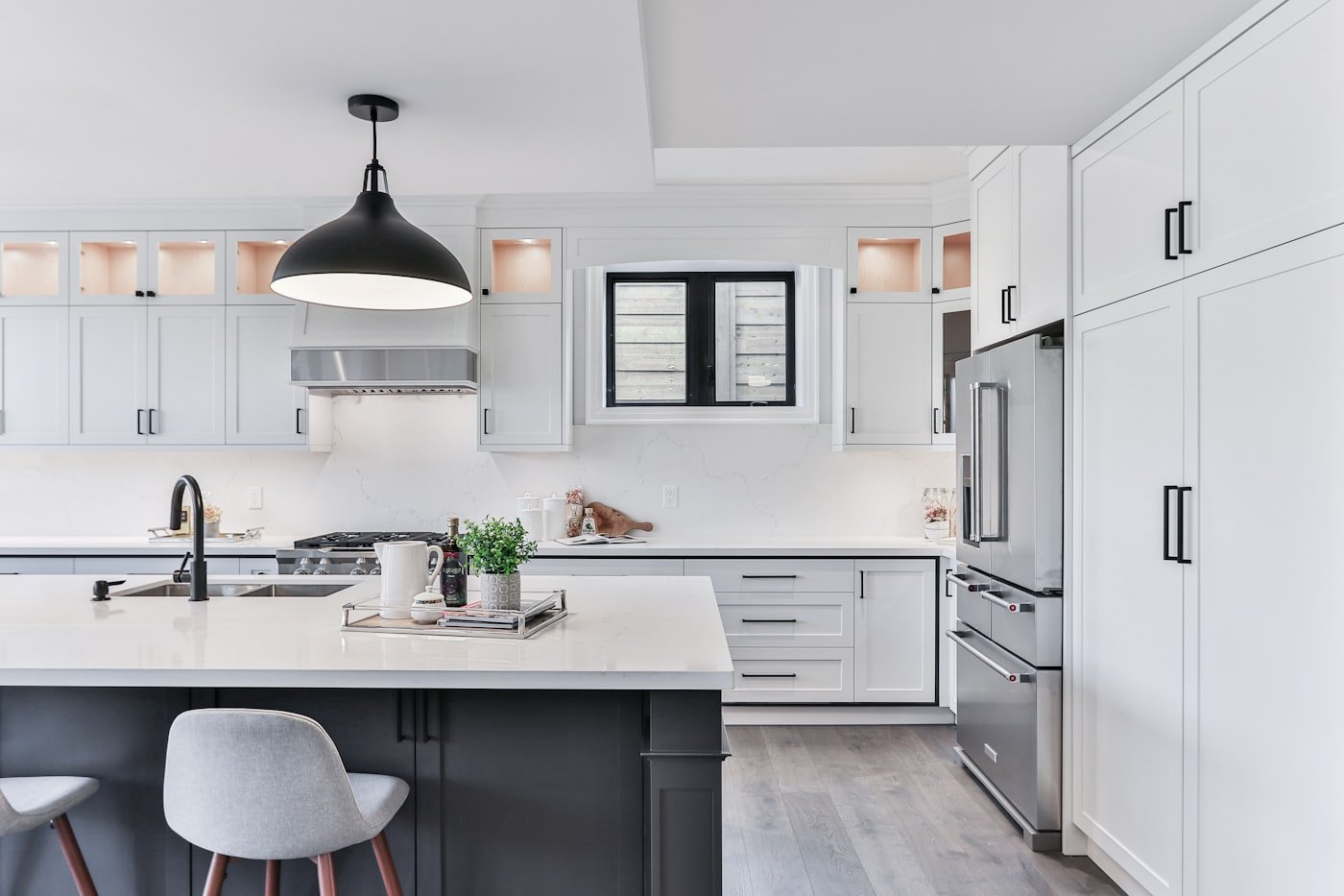 Large kitchen with dark forest green cabinets and a marble island