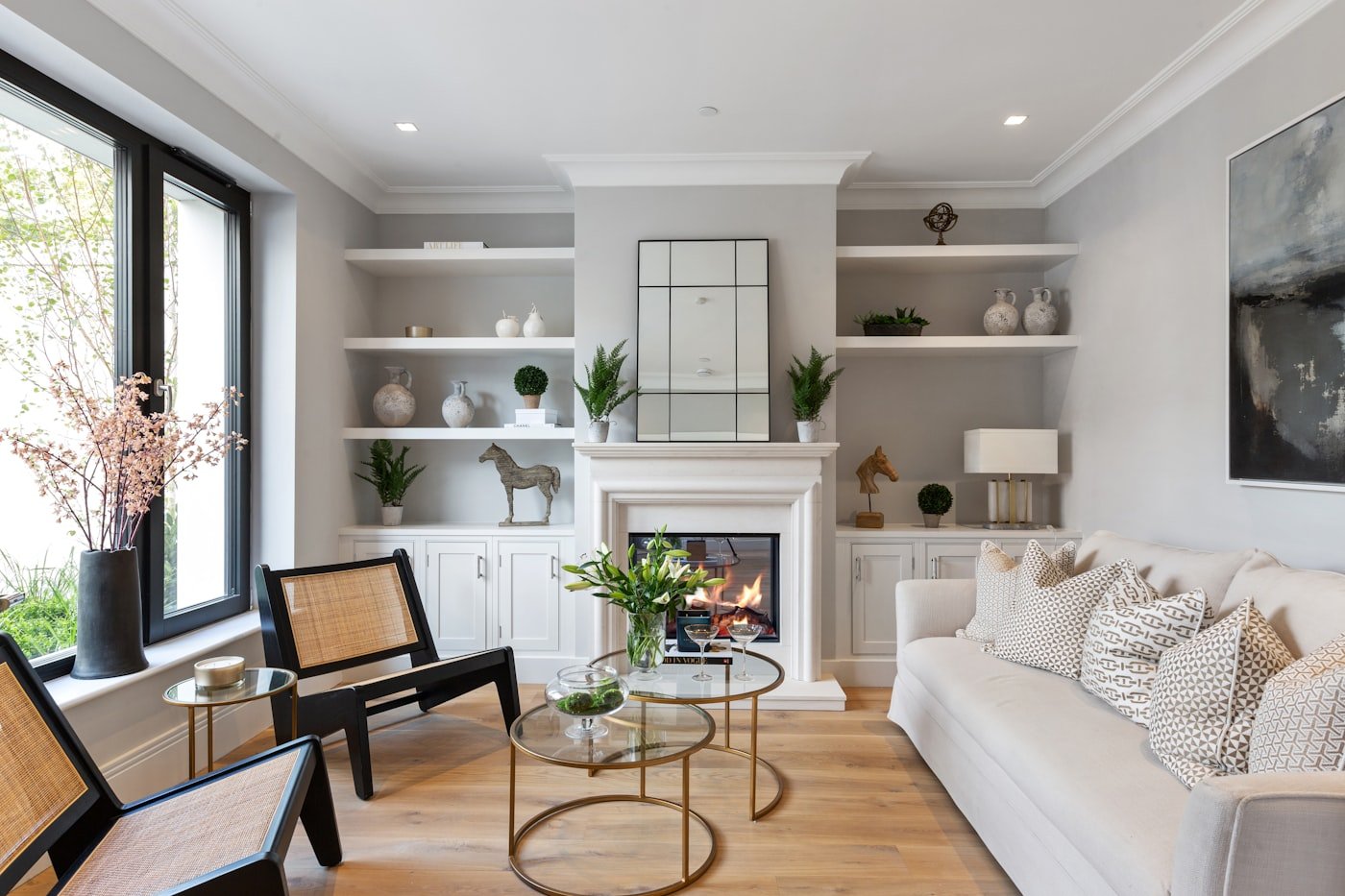 Living room with tall shelving reaching the ceiling beside a window
